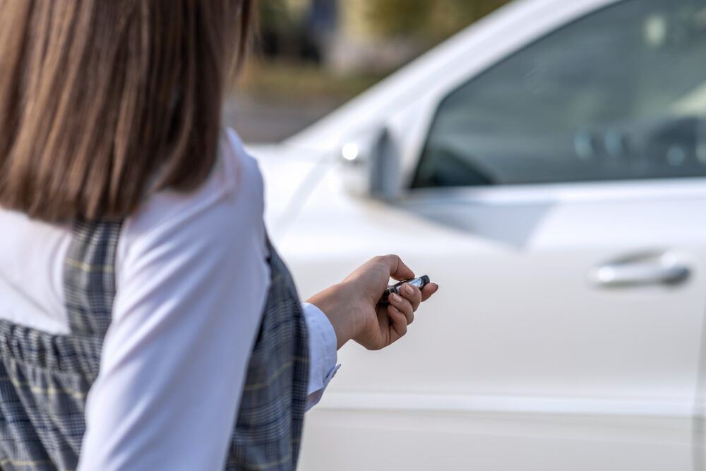 Redhead girl unlocking a car with wireless key.